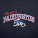 Close-up of a navy blue fabric garment featuring a printed graphic that reads 'Be more PADDINGTON' in red and white outlined letters, with a cartoon Paddington bear wearing a red hat and blue outfit reclining on a striped chair.