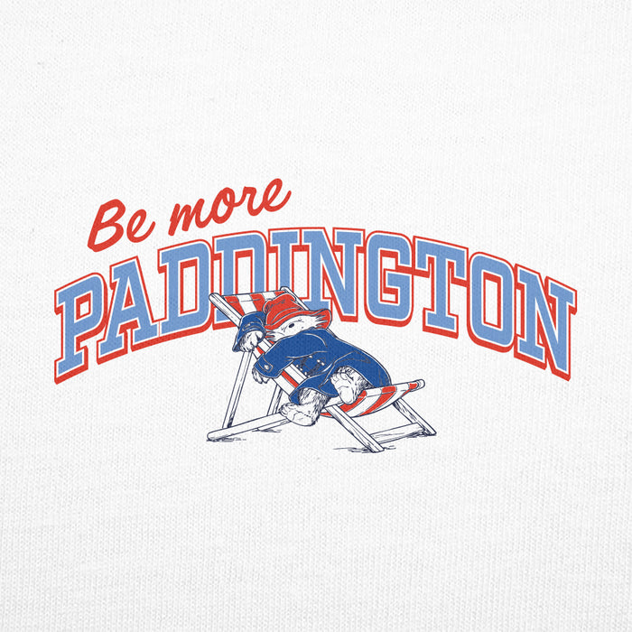 A close-up of a white textured fabric featuring a printed graphic that reads 'Be more PADDINGTON' in red and blue lettering, with a cartoon rabbit in a blue and red outfit sitting in a folding chair.