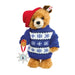 Teddy bear wearing a blue sweater with white snowflake patterns, holding a decorative ornament on a white background.