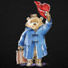 Illustration of a bear in a blue coat and red hat holding a suitcase on a black background