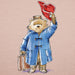 Illustration of a teddy bear in a blue coat and red hat on a pink background