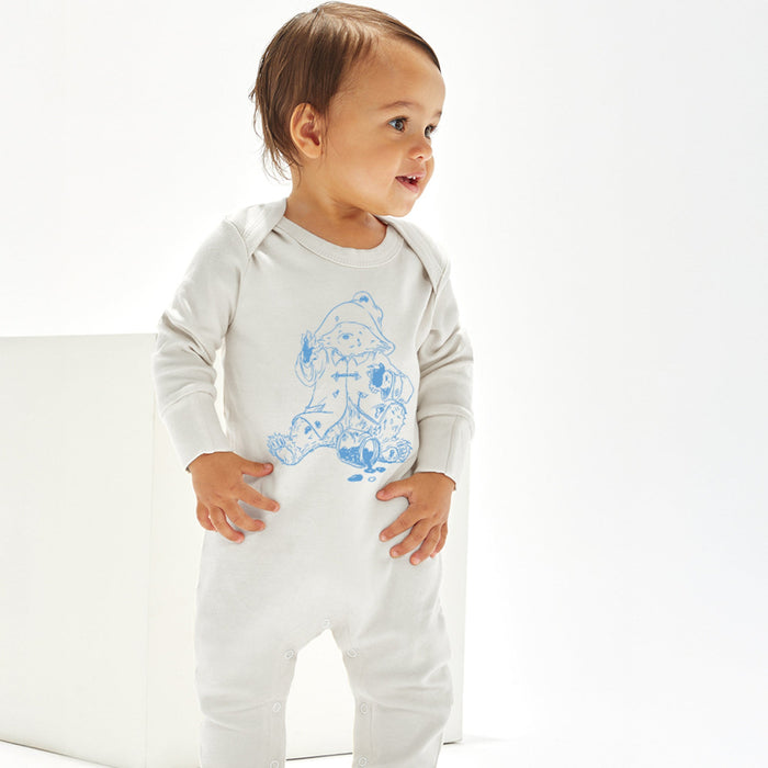 Baby wearing a white onesie with a blue bear design on a white background