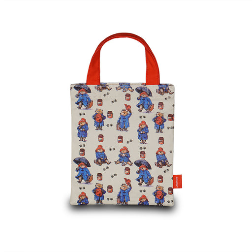 Small tote bag with paddington bear pattern and red handles on a white background