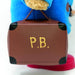 Small brown suitcase with 'P.B.' on it, held by a blue plush Paddington bear toy.