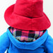 Close-up back shot of Paddington bear wearing a red hat and blue coat with plaid lining.