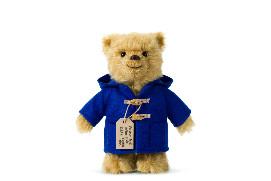 Paddington Teddy bear wearing a blue coat with a label on a white background