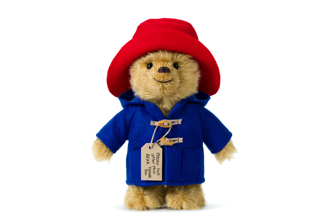 Stuffed Paddington teddy bear toy wearing a red hat and blue coat on a white background