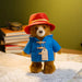 Stuffed Paddington teddy bear in a blue coat and red hat on a map with books in the background