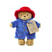 Plush toy Paddington bear in a blue coat and red hat with a tag on a white background