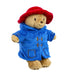 Stuffed toy Paddington bear wearing a blue coat and red hat on a white background
