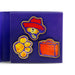Set of colorful pins featuring a bear with a red hat, paw print, and orange suitcase on a blue card.
