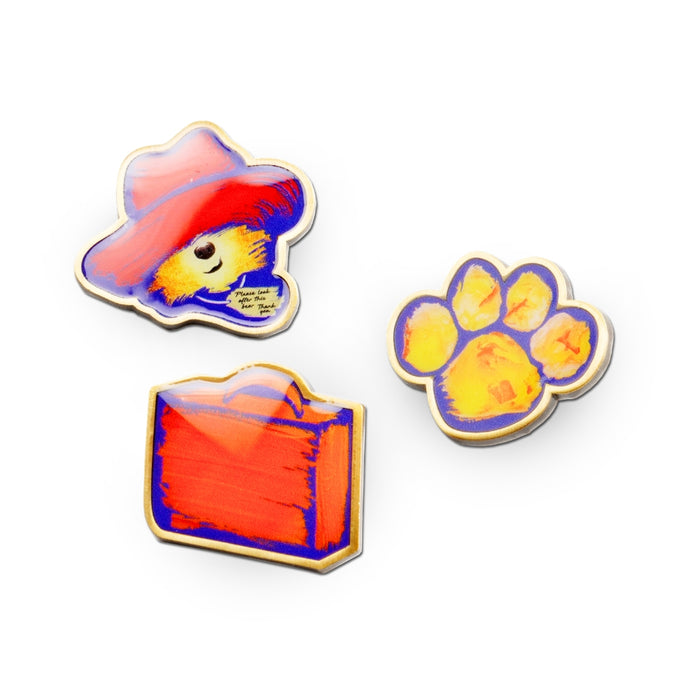 Three colorful paddington the musical enamel pins on a white background
