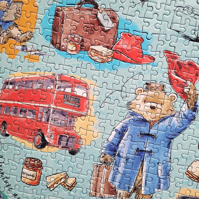 Jigsaw puzzle with a bear, red bus, and suitcase on a blue background