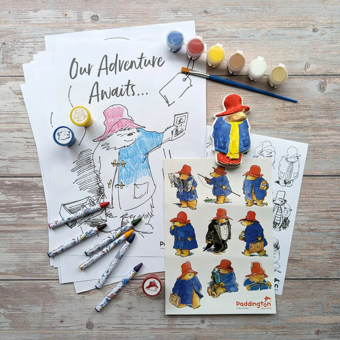 Paddington Art Set with Coloring pages, paints, stickers, stamps and stickers with Paddington Bear on a wooden surface.
