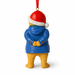 A Christmas ornament shaped like Paddington bear seen from the back, wearing a red Santa hat with white trim, a blue winter coat, yellow fur, and a red hanging ribbon.