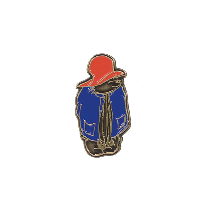 A pin badge featuring an illustration of Paddington bear in his iconic blue duffel coat and red hat.