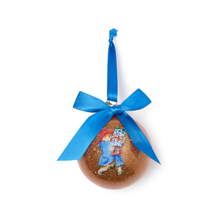 Decorative ornament with a blue ribbon and a design of Paddington bear carrying packages on a white background