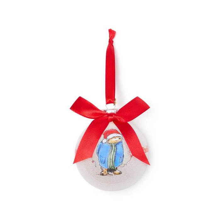 Round pink Christmas ornament with a Paddington bear design and red ribbon on a white background