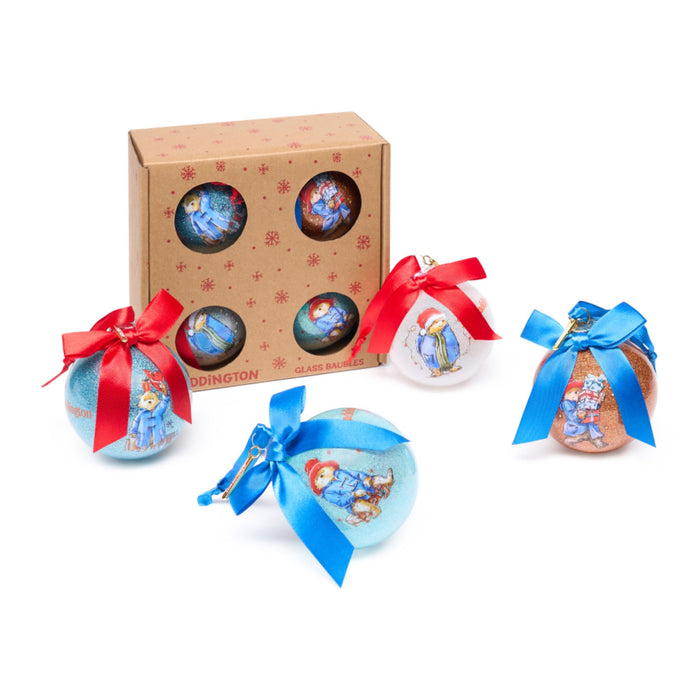 Set of Paddington Christmas bauble ornaments with red and blue ribbons in front of a box containing more ornaments.