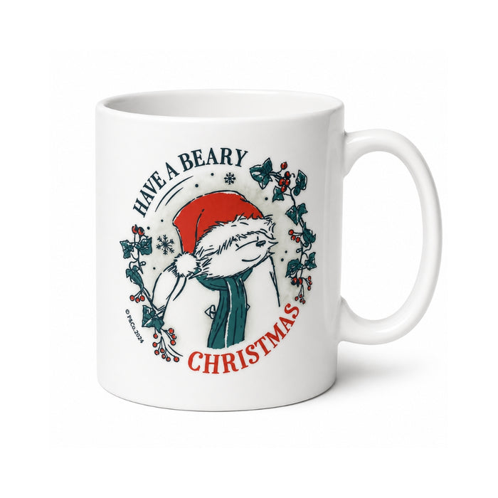 A white ceramic mug featuring a festive illustration of a Paddington bear Christmas character wearing a red Santa hat and green scarf, surrounded by holly leaves and the text 'HAVE A BEARY CHRISTMAS'.