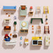 A collection of miniature wooden dollhouse furniture pieces and accessories arranged neatly on a light pink background. The set includes a blue sofa, a bed, chairs, tables, a bathroom vanity, a kitchenette, a bathtub, a lamp, a rug, and Paddington Bear character.
