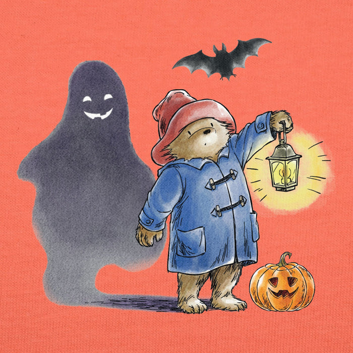 Illustration of Paddington bear in a blue coat with a lantern, ghost, bat, and pumpkin on an orange background
