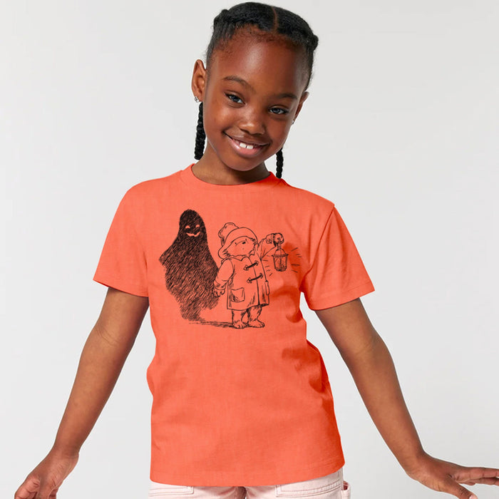 Child wearing an orange Halloween t-shirt with a black Paddington graphic design on a plain background