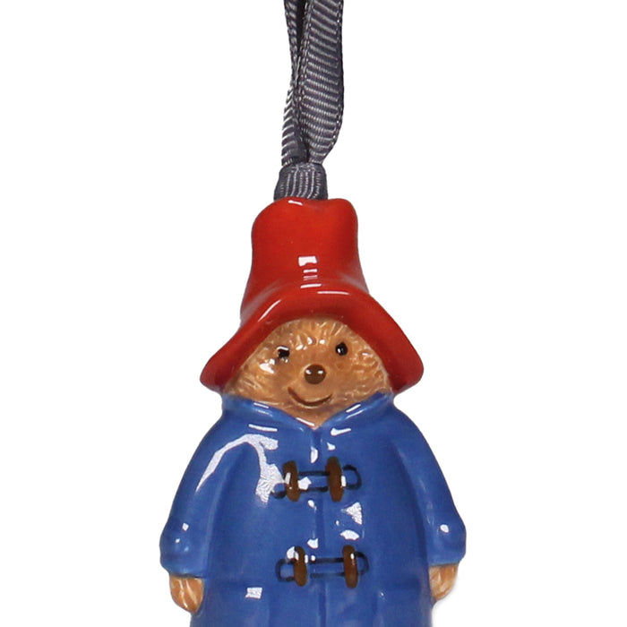 Decorative ornament of a bear wearing a blue coat and red hat on a white background