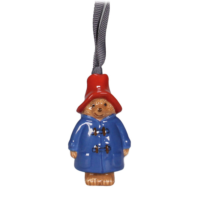 A hanging decoration featuring a figurine of Paddington Bear in a blue coat and a red hat, with a red cord for hanging.