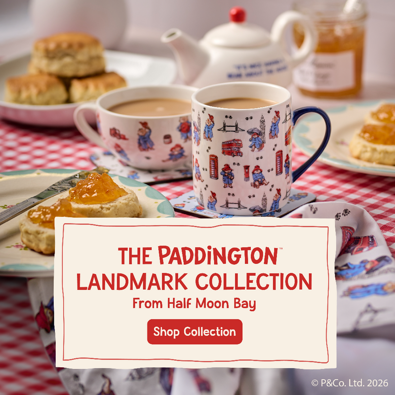 Tea cups with Paddington Bear design on a table with tea and biscuits, featuring the Paddington Landmark Collection from Half Moon Bay.