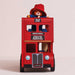 A red double-decker toy bus with a Paddington Bear figure sitting on top, photographed against a plain light beige studio background.