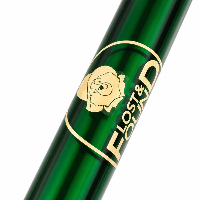 Close-up of a glossy dark green ballpoint pen with a gold circular Paddington logo and the visible text 'LOST & FOUND' on a white background.