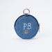 A circular blue denim coin purse with a silver metal key ring and zipper, featuring white embroidered 'P.B.' and bear pawprint