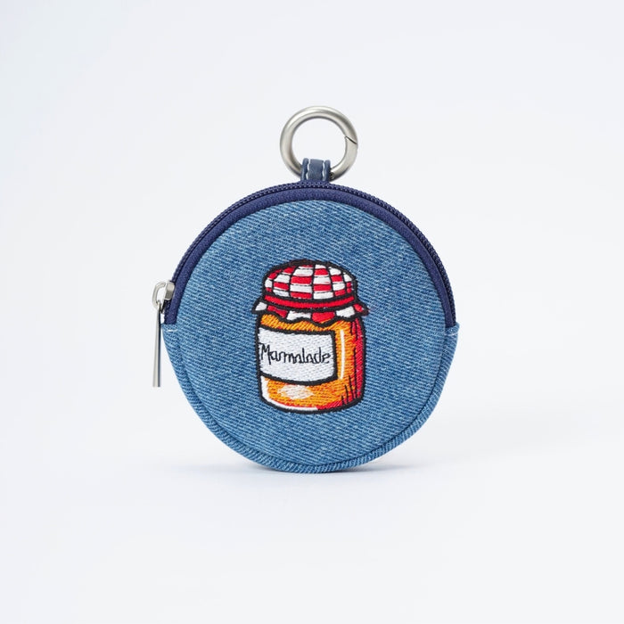 A round blue denim coin purse with a zipper closure and a silver metal key ring. The front features an embroidered design of a orange marmalade jar with a red-and-white checkered lid and a label reading 'Marmalade'.