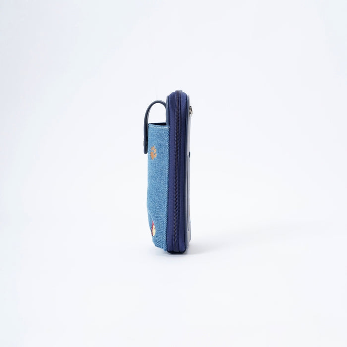 A blue denim and navy phone pouch with small embroidered Paddington bear face, shown from the side on a white background.