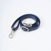 A navy blue faux leather shoulder strap with white contrast stitching, featuring silver metal hardware including a swivel snap hook and a rectangular buckle, displayed on a clean white background.