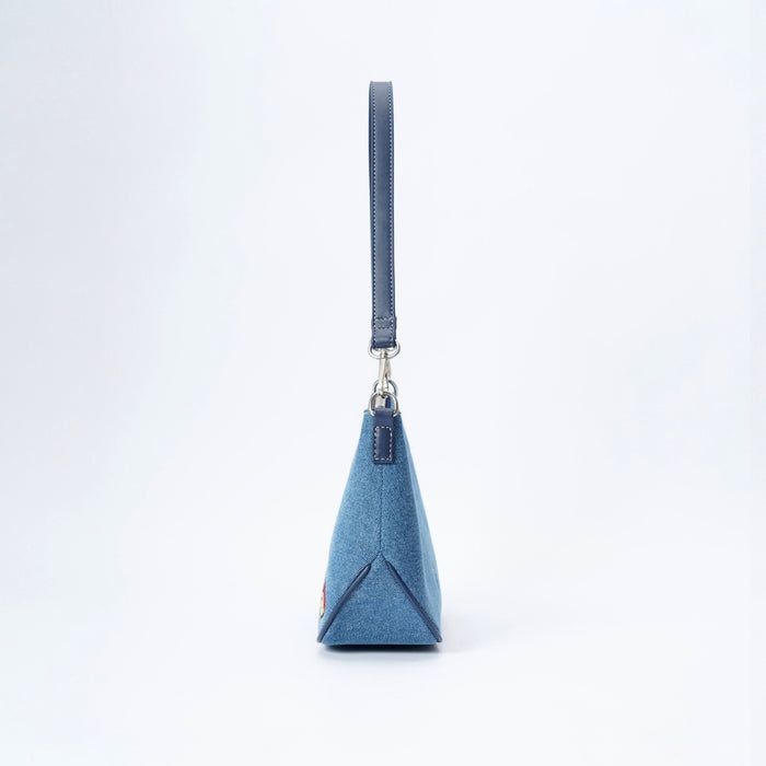A blue denim Paddington bear handbag with a matching blue strap and silver-tone hardware, shown from the side on a white background.