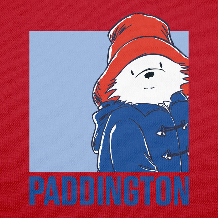 A close-up of a red fabric surface featuring a printed graphic of Paddington Bear wearing a red hat and blue coat, with the word 'PADDINGTON' in large blue letters at the bottom.