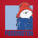 A close-up of a red fabric surface featuring a printed graphic of Paddington Bear wearing a red hat and blue coat, with the word 'PADDINGTON' in large blue letters at the bottom.