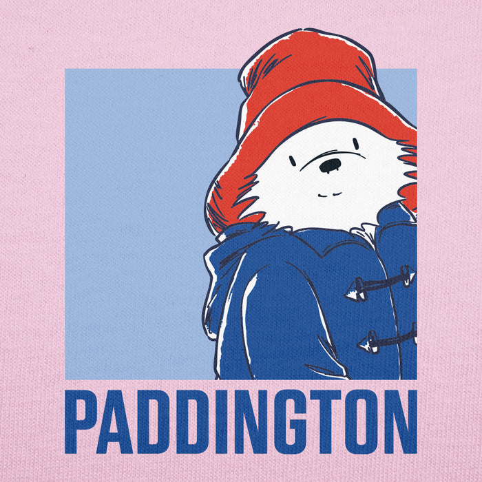 A square graphic print featuring the Paddington bear character wearing a red hat and blue coat, centered on a light pink background with the word 'PADDINGTON' in large blue letters at the bottom.