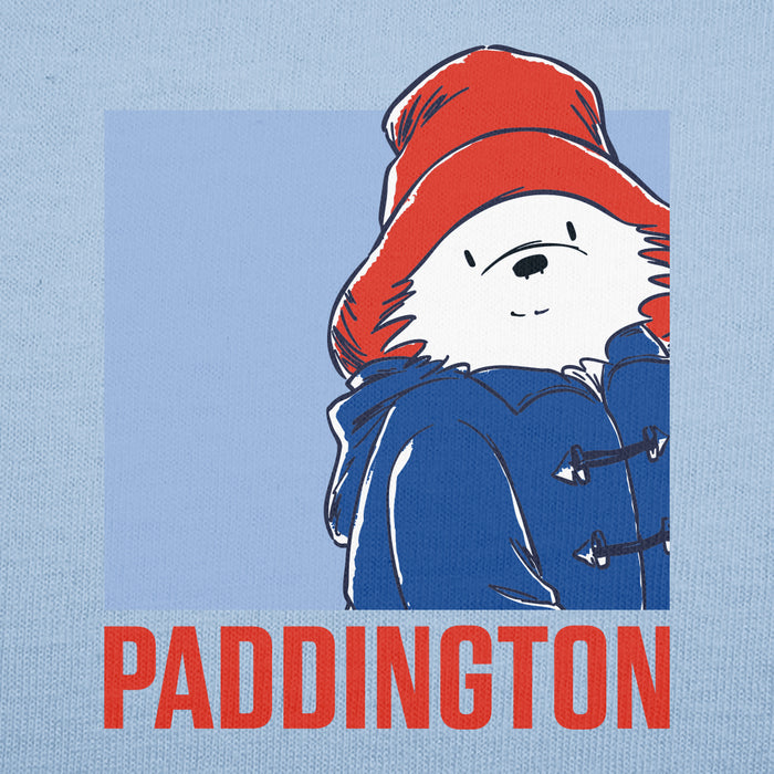 A graphic print featuring the Paddington Bear character wearing a red hat and blue coat, with the word 'PADDINGTON' in large red letters below, set on a light blue textured background.