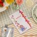 A5 Notebook with floral design and 'Paddington' text on a table setting with fruit, flowers, and cutlery.