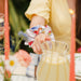 Person wearing a floral paddington bear scrunchie with a blurred background of a table setting.