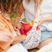 Two children playing with a colorful Paddington bear bag outdoors