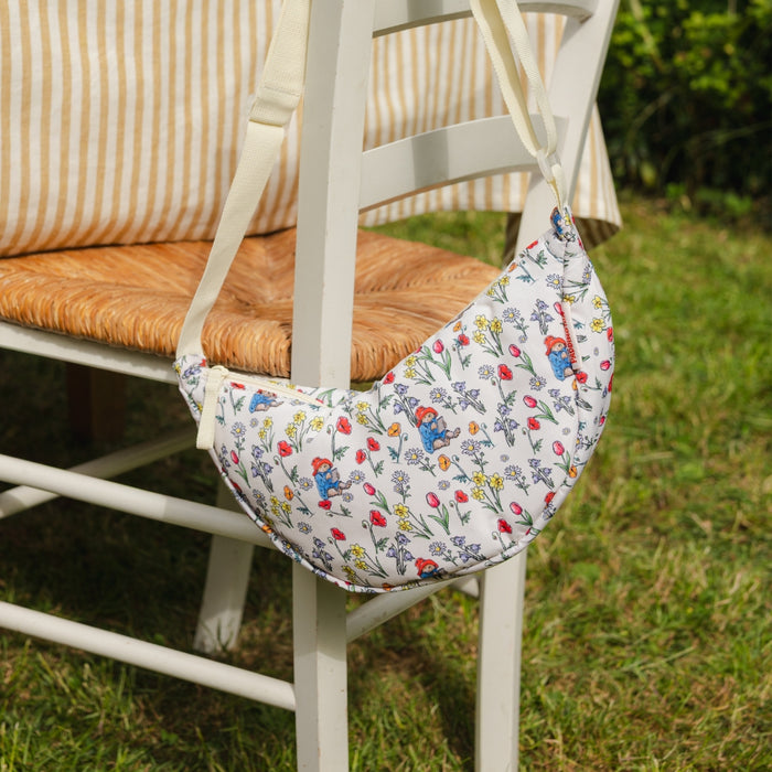 Floral-patterned crossbody Paddington bear bag attached to a chair outdoors on grass