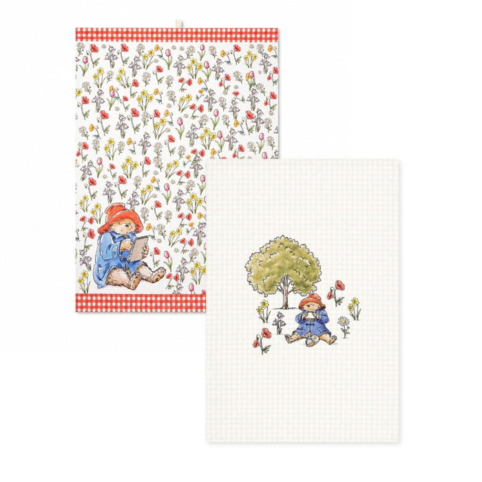 Two tea towels with Paddington and floral illustrations and patterns on a white background
