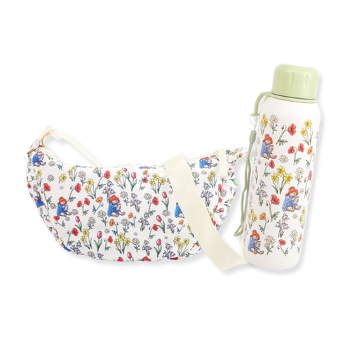 A matching floral print moon bag and water bottle set. The white fabric crossbody bag features a colorful print of paddington bear and wildflowers, with a cream shoulder strap.