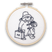 A mini embroidery kit depicting an illustration of Paddington bear with a suitcase and hat, holding a jar of marmalade, mounted on a hoop.