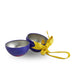 A small round metal fillable christmas bauble shown open, with a deep blue exterior, silver-toned interior, and a bright yellow ribbon tied in a bow, photographed on a plain white background.