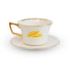 A white ceramic teacup and saucer set with gold trim, featuring a marmalade sandwich illustration on the cup and gold text inside the rim.